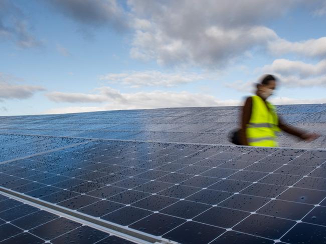 (FILES) In this file photo taken on December 08, 2020, a woman walks through the solar pannels of a photovoltaic power plant installed by Generale du Soleil (GDS) and operated by Energ'iV SEML in a former landfill of waste in Guignen, western France. - In the midst of the debate on European energy sovereignty, the Lyon-based industrial start-up Carbon is preparing an ambitious "gigafactory" project with 10,000 employees that would produce photovoltaic panels, which are currently imported massively from Asia, in a fully integrated manner in France by 2030. (Photo by Loic VENANCE / AFP)