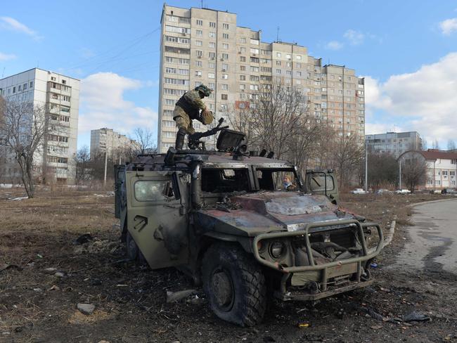 A Ukrainian Territorial Defence fighter examines a destroyed Russian Armoured personnel carrier after the fight in Kharkiv. Picture: Sergey Bobok / AFP