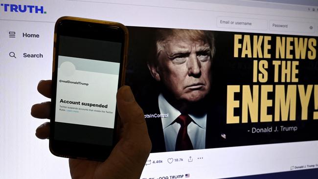 The previously suspended Twitter account of Donald Trump is displayed on a mobile phone with the former President Trump's Truth's page shown in the background. He has been posting on his own site, Truth Social, after being banned from other social media. Picture: AFP