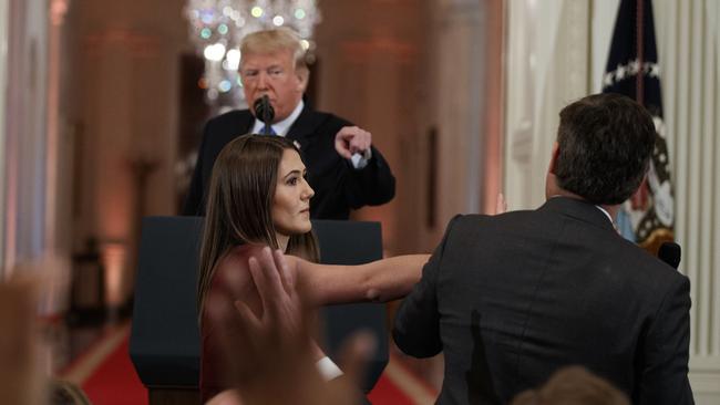 Donald Trump looks on as a White House intern attempts to take away the microphone from CNN journalist Jim Acosta during the news conference.