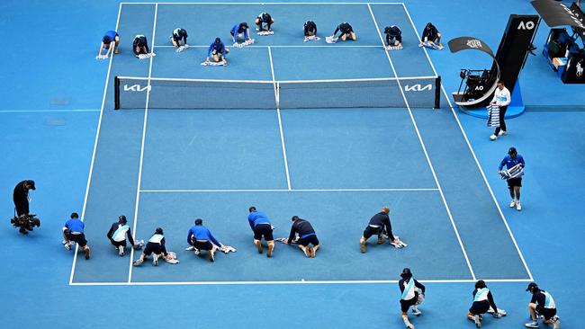 Staff and volunteers help to dry the court after a rain shower at the Australian Open in Melbourne. Picture: Paul Crock/AFP