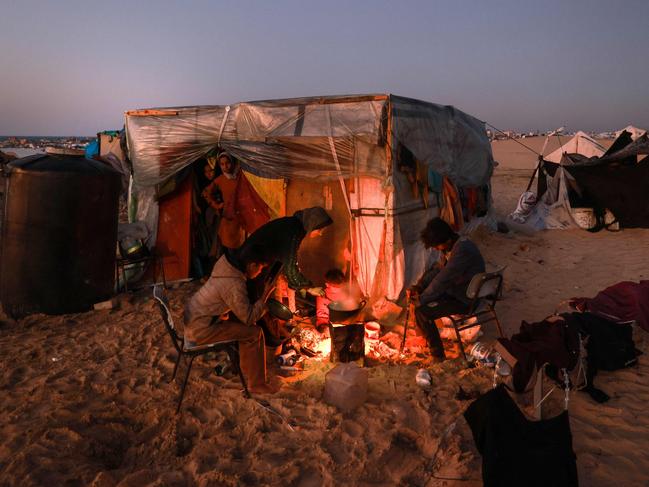 TOPSHOT - Displaced Palestinians prepare an iftar meal, the breaking of fast, on the first day of the Muslim holy fasting month of Ramadan, outside a tent in Rafah in the southern Gaza Strip on March 11, 2024, amid ongoing battles between Israel and the militant group Hamas. (Photo by MOHAMMED ABED / AFP)