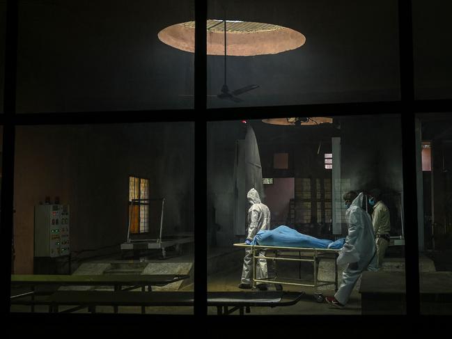 Ambulance staff carry the dead body of a person who died from coronavirus, inside a crematorium in New Delhi. Picture: AFP