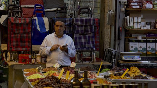 A shop owner takes a break on his phone inside the Jerusalem markets