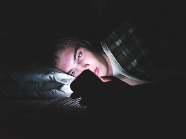 Generic image of child in bed with mobile phone