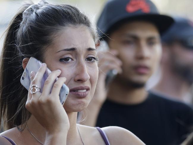 People speak on their phones as they stand on a street in Barcelona, Spain. Picture: AP