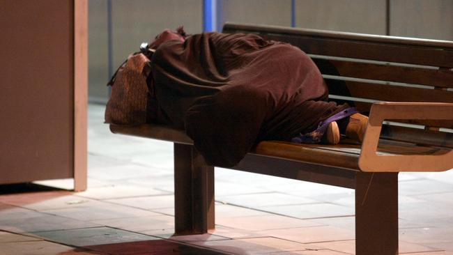 A homeless person sleeping on a bench.