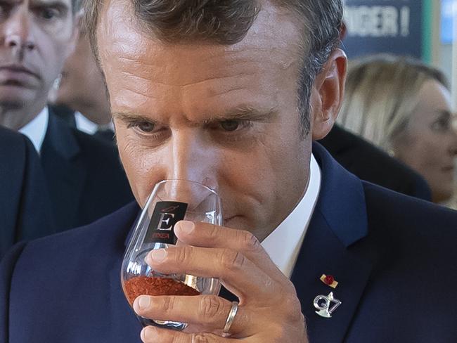 French President Emmanuel Macron samples local wine as he tours the exhibition hall above the international press center on the opening day of the G7 summit. Picture: AP