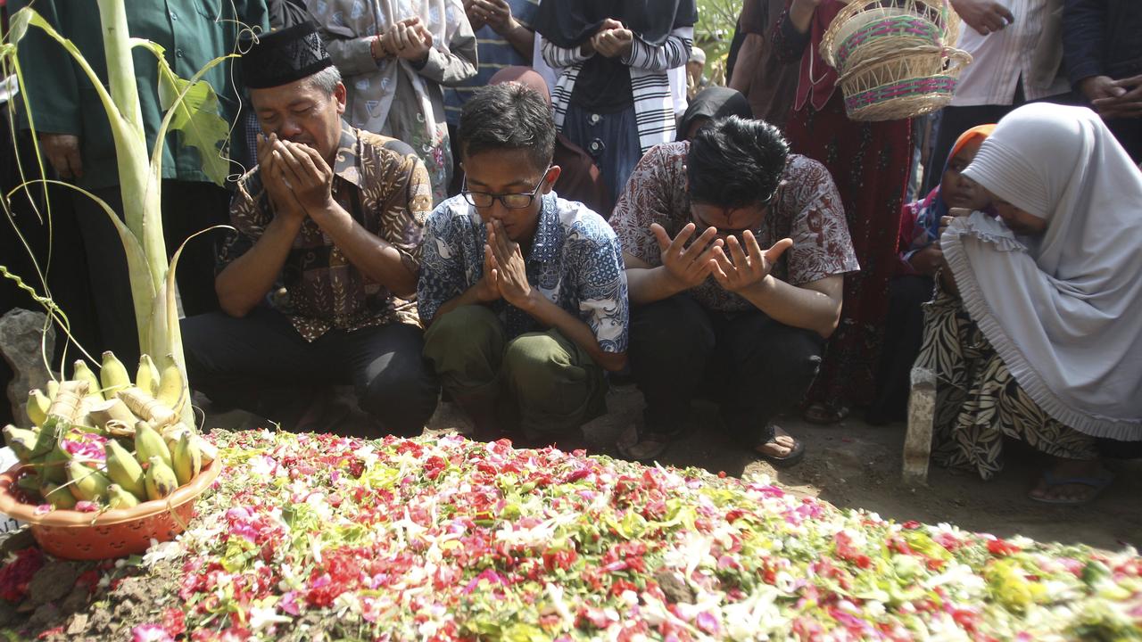 Bambang Supriyadi, left, the father of Jannatun Cintya Dewi, a victim of a Lion Air plane crash, prays at the grave of his daughter during her funeral in Sidoarjo, Indonesia. Photo: AP Photo/Trisnadi