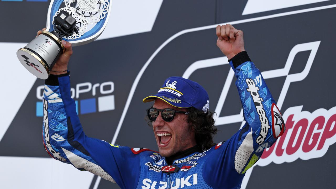 Alex Rins holds up the trophy on the podium as he celebrates victory at Silverstone.