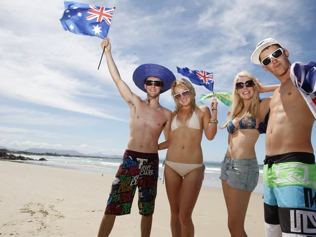 (L-R) Luke Streets, Honnie Harris, Sophie Eade and Tyson Skipper, from Launceston in Tasmania, pose for portrait holding Australia day flags at Main Beach, Byron Bay. Photo Jerad Williams / The Northern Star