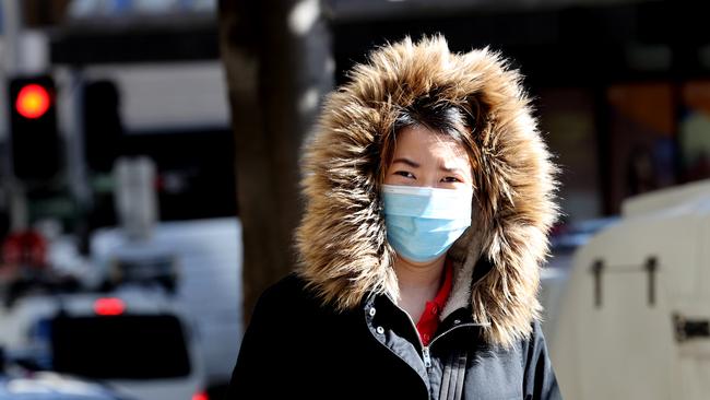 A woman walks on Liverpool Street wearing a mask and a parka. in Sydney. Picture: Dylan Coker