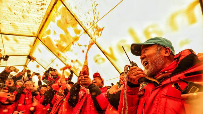 Colleagues at the base camp celebrate after a group of Chinese surveyors reached the summit of Mount Everest on May 27, 2020. (Photo by STR / AFP) /