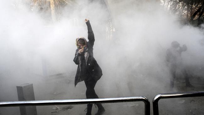 A university student attends a protest inside Tehran University while a smoke grenade is thrown by anti-riot Iranian police, in Tehran, Iran on Saturday. (Pic: AP Photo)