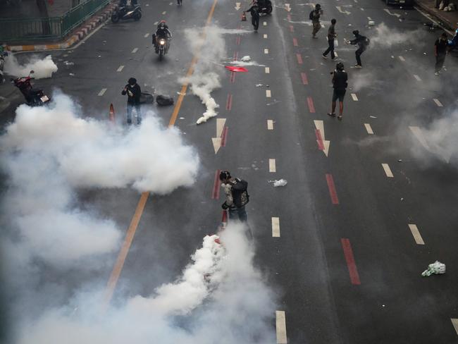 Protesters return tear gas canisters to riot police in Bangkok. Picture: Getty Images