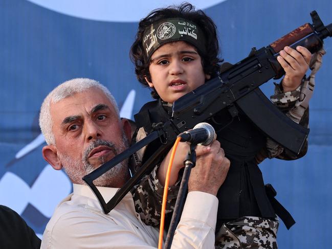 (FILES) Hamas leader Yahya Sinwar holds the child of an Al-Qassam Brigades fighter, who was killed in the recent fighting with Israel, with a Kalashnikov rifle in his hand during a rally in Gaza City on May 24, 2021. An Israeli security official told AFP on October 17, 2024 that the military was conducting a DNA test on a militant's body to confirm whether it was Hamas chief Yahya Sinwar. (Photo by Emmanuel DUNAND / AFP)