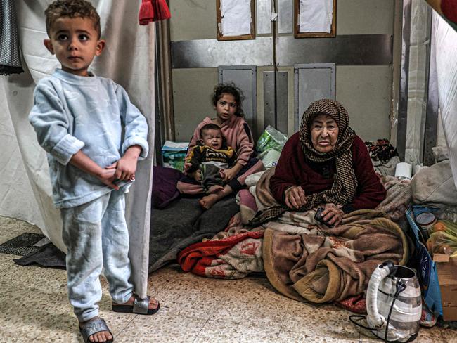 An elderly woman looks on as she sits with children at a makeshift camp in an area of the European Hospital in Khan Yunis. Picture: AFP