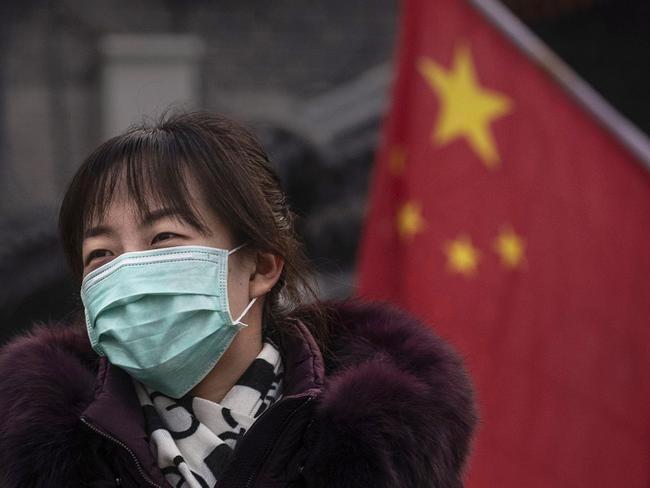 BEIJING, CHINA - JANUARY 26: A Chinese woman wears a protective mask as she walks by a flag and lantern placed for the Chinese New Year holiday on January 26, 2020 in Beijing, China. The number of cases of a deadly new coronavirus rose to over 2000 in mainland China Sunday as health officials locked down the city of Wuhan earlier in the week in an effort to contain the spread of the pneumonia-like disease. Medical experts have confirmed the virus can be passed from human to human. In an unprecedented move, Chinese authorities put travel restrictions on the city, which is the epicenter of the virus, and neighboring municipalities affecting tens of millions of people. The number of those who have died from the virus in China climbed to at least 56 on Sunday, and cases have been reported in other countries including the United States, Canada, Australia, France, Thailand, Japan, Taiwan and South Korea. (Photo by Kevin Frayer/Getty Images)