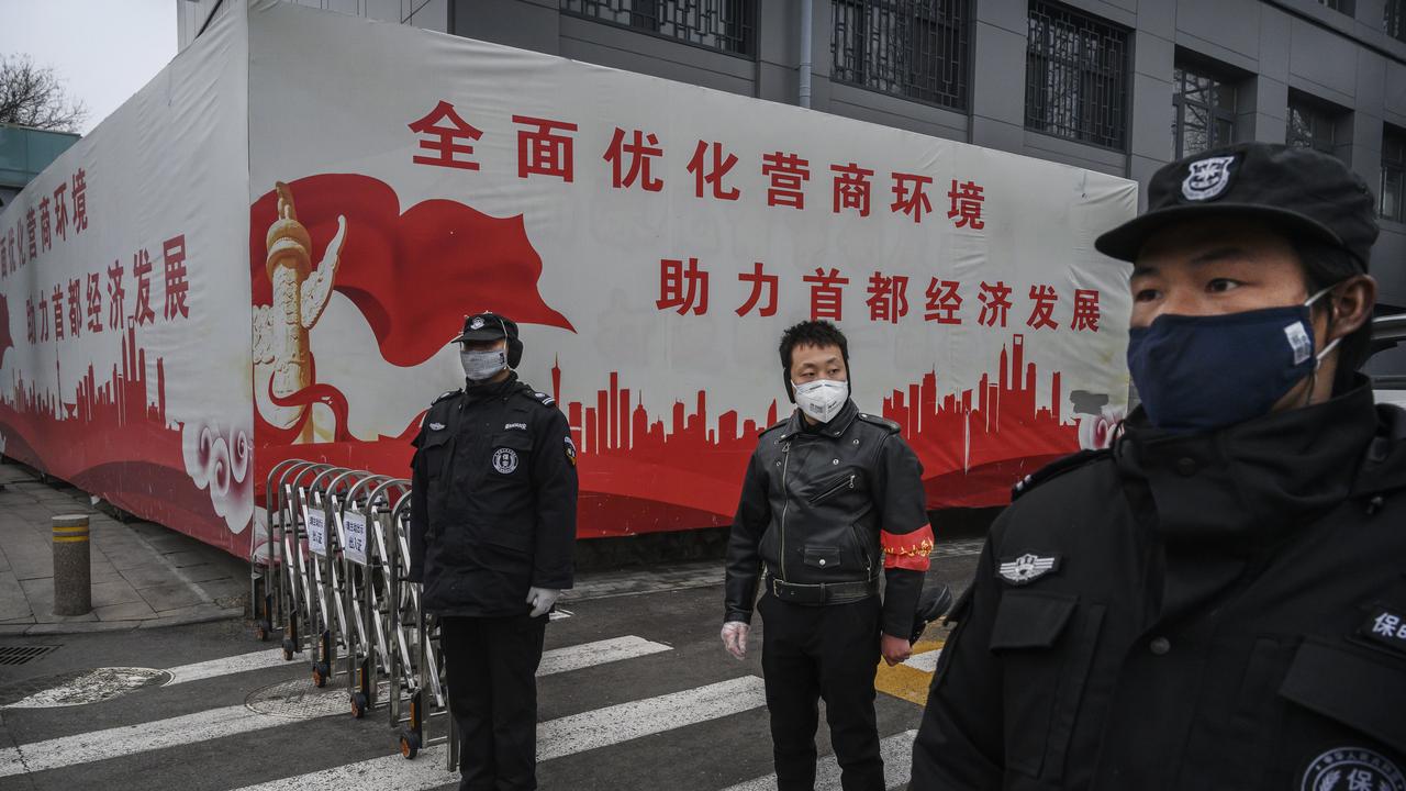 A Chinese man who is a member of the neighbourhood committee centre and security guards wear protective masks as they control entry and exit from a residential area in Beijing, China. Picture: Kevin Frayer/Getty Images