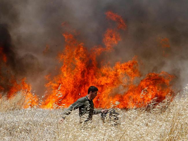 An Israeli soldier attempts to extinguish a fire in a wheat field near the Kibbutz of Nahal Oz, along the border with the Gaza Strip. Picture: AFP