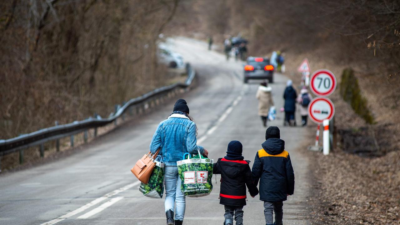 A woman with two children and carrying bags walk on a street to leave Ukraine after crossing the Slovak-Ukrainian border in Ubla, eastern Slovakia, close to the Ukrainian city of Welykyj Beresnyj, on February 25, 2022, following Russia's invasion of the Ukraine. - Ukrainian citizens have started to flee the conflict in their country one day after Russia launched a military attack on neighbouring Ukraine. (Photo by PETER LAZAR / AFP)