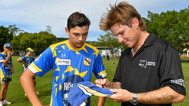 Australian international cricketer Adam Zampa signs Marist Brothers cricketer Theo Rogusz's cap at the Mortimer Oval nets in Lismore.