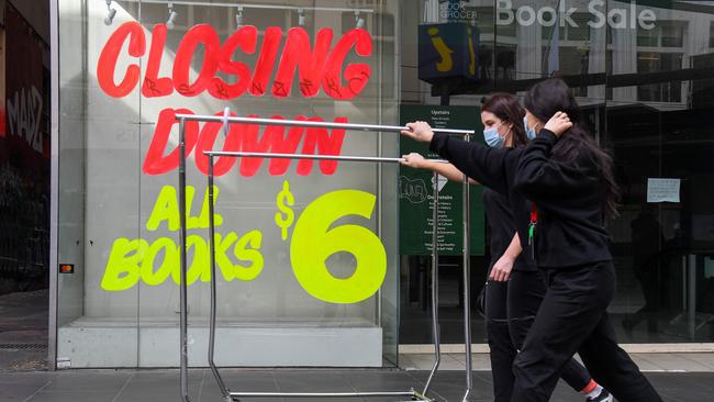 Workers push trolleys past an empty shop in Melbourne’s CBD. Retail stores are permitted to operate contactless ‘click and collect’ and delivery services. Picture: AFP