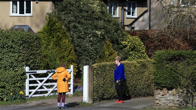 Two women stand a distance apart as they talk in Stoney Middleton village, in Derbyshire. Picture: AFP.