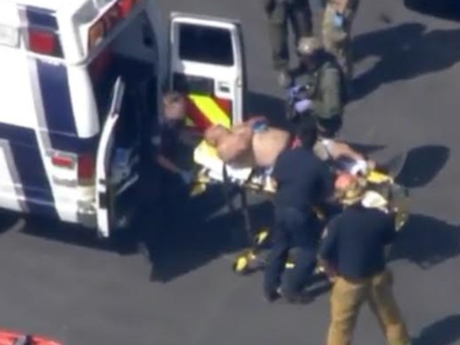 A male, believed to be the injured guard, is transported to an ambulance following the home invasion. Picture: KTLA 5