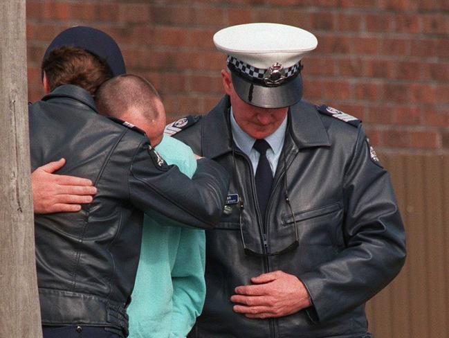 Emotional officers place flowers at the murder scene. Picture: John Hart