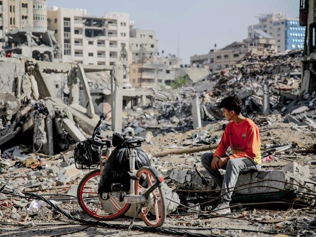 A Palestinian youth sits next to his bicycle amid the rubble of destroyed buildings in Gaza City on the northern Gaza Strip following weeks of Israeli bombardment, as a four-day ceasefire took effect. Picture: AFP