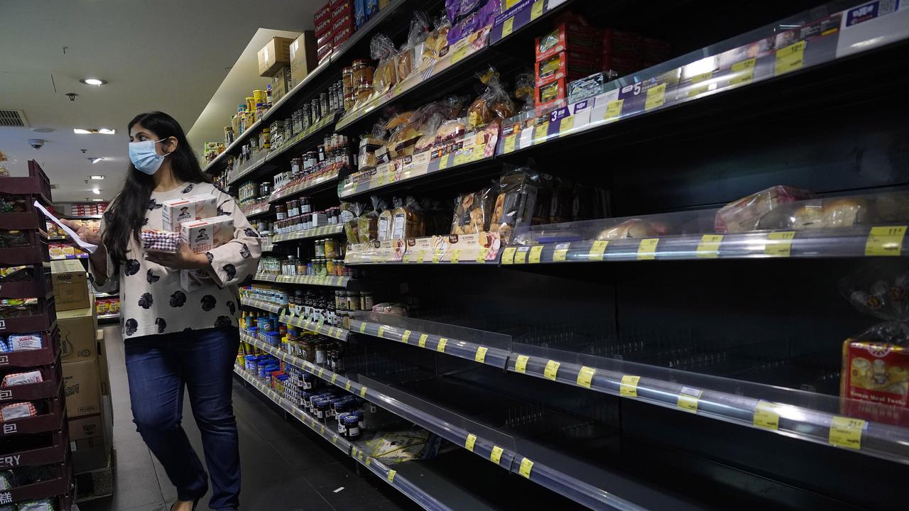 A woman walks past an empty shelf for breads at a supermarket in Hong Kong, Saturday, Feb. 15, 2020. China reported Saturday a figure of 2,641 new virus cases, a major drop from the higher numbers in recent days since a broader diagnostic method was implemented. (AP Photo/Vincent Yu)