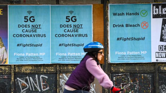 A cyclist past public service announcement posters debunking a conspiracy that 5G telecommunications technology causes coronavirus. Picture: William West/AFP