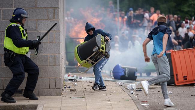 Riot police officers push back anti-migration protesters outside the Holiday Inn Express Hotel housing asylum seekers in Rotherham, England.