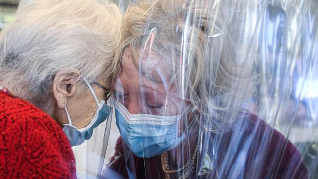 A resident of the Domenico Sartor nursing home in Castelfranco Veneto, near Venice, hugs her visiting daughter, right, through a plastic screen in a “Hug Room” last November as the second wave erupted in Italy. Picture: AFP