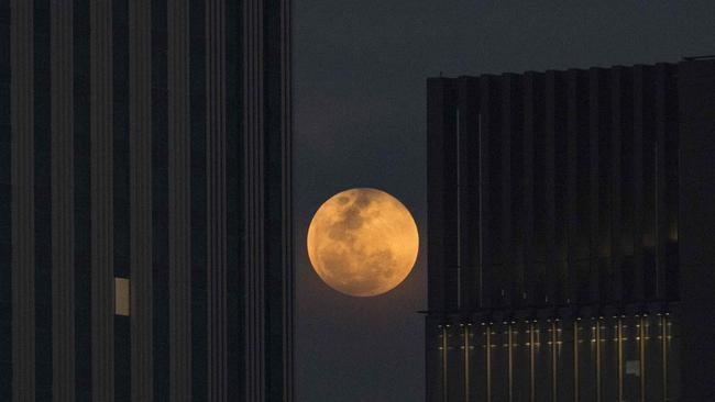 TOPSHOT - The moon rises between two office buildings in Bangkok. Picture: AFP