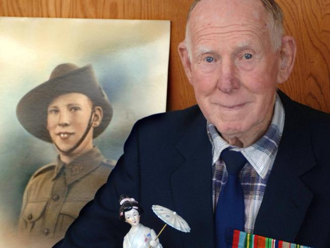 Allan Chick pictured with his medals and a Japanese porcelain doll at his home in Heyfield. Behind him is a 1940 portrait of himself taken when he was 20 yrs old.