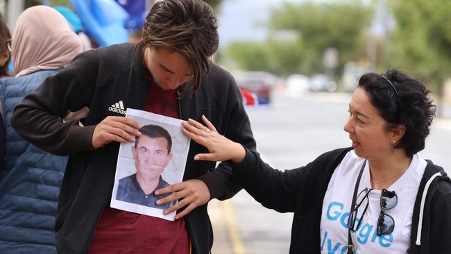 Protester Imran Omarhoja with Ramila Chanisheff in front of the Overseas Chinese Association in Findon, SA, with a photo of a missing family Uyghur member. Picture: Russell Millard.