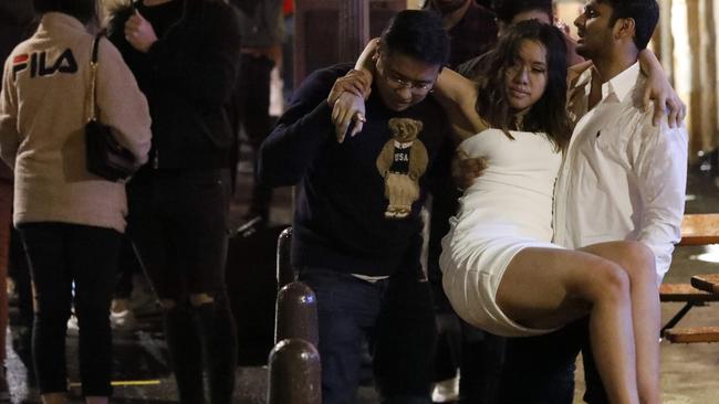 A woman is carried out past a crowd of people queuing up outside the Argyle in the Rocks on Saturday. Picture: Damian Shaw