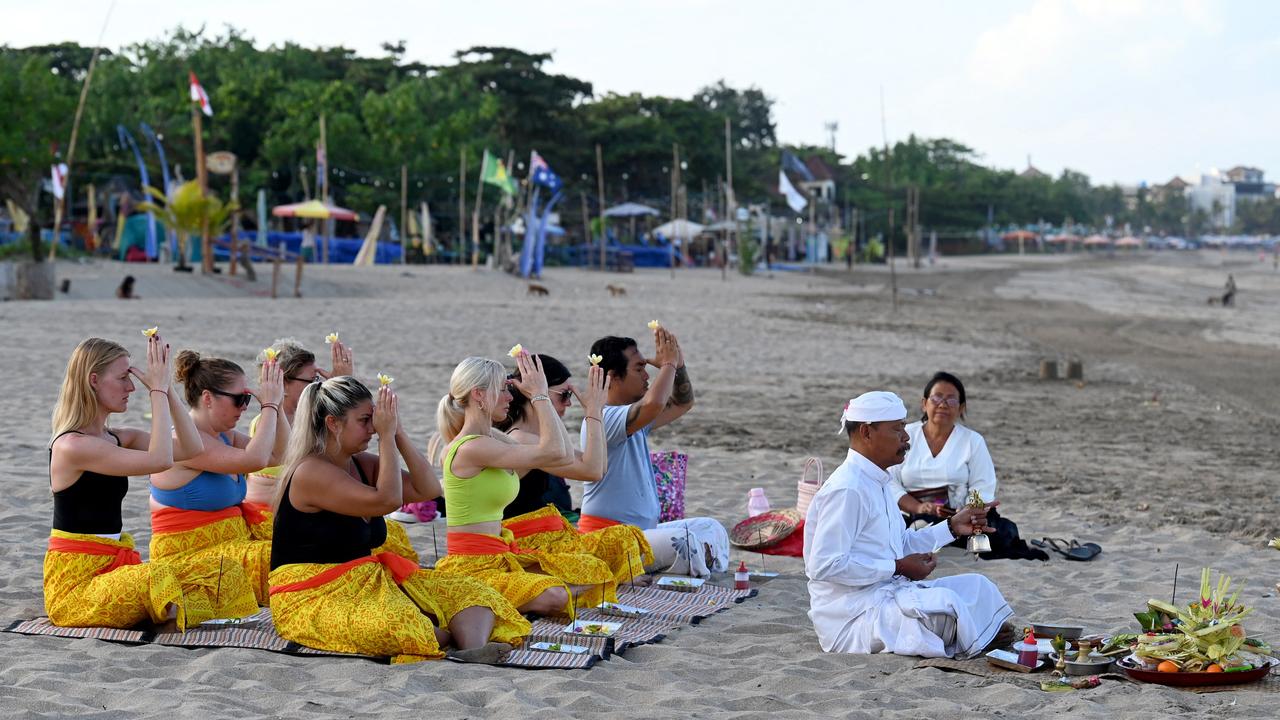 Tourists participate in a Balinese Hindu prayer gathering on a beach in Seminyak near Denpasar, Bali. Picture: Sonny Tumelaka/AFP