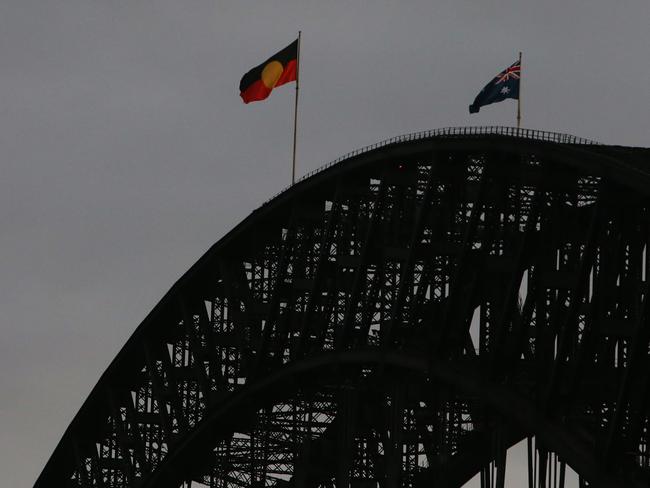 The Aboriginal flag flies alongside the Australian flag on the Sydney Harbour Bridge to mark Australia Day. Picture: Lisa Maree Williams/Getty