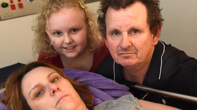 Jodie BurnsÂ was hit in the head by a football while line lining up for tickets to see the Carlton and GWS clash at Etihad. She is comforted at the Royal Melbourne Hospital by her husband, Colin Boyd and daughter, Laura Boyd. Picture; Tony Gough