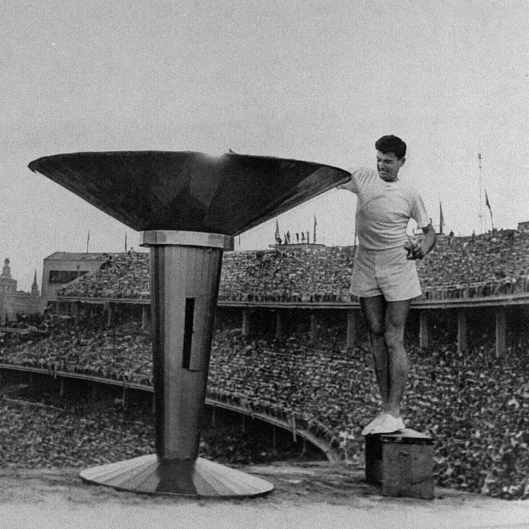 Junior mile record holder, athlete Ron Clarke took flame at entrance to stadium, & carrying special ceremonial torch, now in International Olympic Committee Museum, Lausanne, circled track & climbed steps to cauldron to light flame at opening ceremony, 1956 Melbourne Olympic Games.Athletes / Athletics                     Olympic56