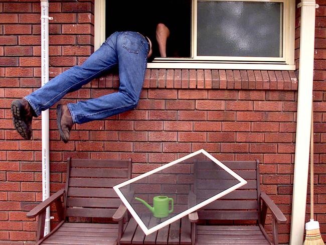 A burglar breaking into house through an unlocked window.