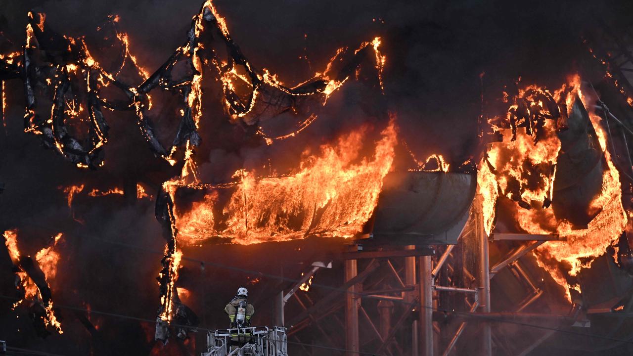 A firefighter is seen on an aerial ladder platform as a fire engulfs a structure of the Oceana Waterworld at the Liseberg Amusement Park in Gothenburg, Sweden on February 12, 2024. (Photo by Born LARSSON ROSVALL / TT News Agency / AFP)