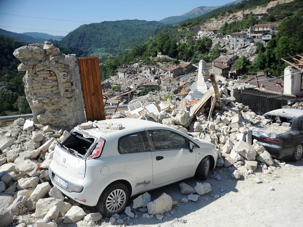 TOPSHOT - Cars sit amidst the rubble from earthquake damaged buildings in the central Italian village of Pescara del Tronto on August 25,2016 a day after a magnitude of between 6.0 and 6.2. earthquake struck the region killing some 247 people. The death toll from a powerful earthquake in central Italy rose to 247 on amid fears many more corpses would be found in the rubble of devastated mountain villages.Rescuers sifted through collapsed masonry in the search for survivors, but their grim mission was clouded by uncertainty about exactly how many people had been staying in communities closest to the epicentre of Wednesday's quake. / AFP PHOTO / MARCO ZEPPETELLA