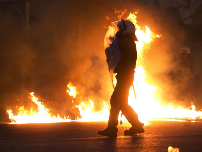 A riot policeman, framed by fire.