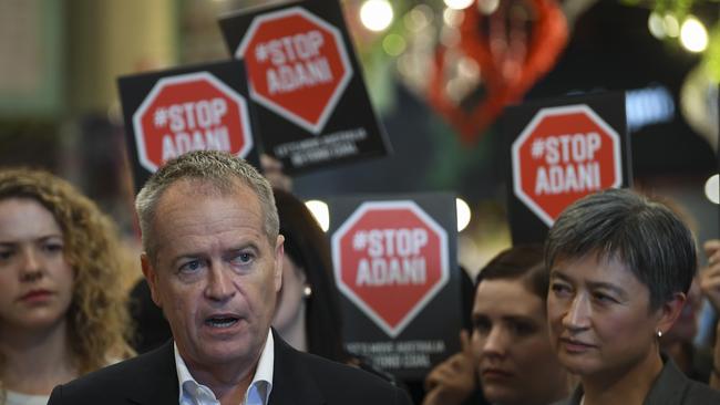 Opposition leader Bill Shorten and Labor Senator Penny Wong are surrounded by activists holding “Stop Adani” signs at Adelaide Central Market. Picture: AAP / Lucas Coch 