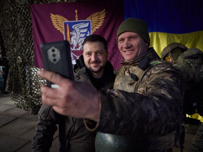 TOPSHOT - This handout picture taken and released by the Ukrainian Presidential press service on December 6, 2022, shows Ukrainian President Volodymyr Zelensky posing for a selfie picture with a Ukrainian soldier as he visits the Donetsk region, amid the Russian invasion of Ukraine. - President Volodymyr Zelensky on December 6, 2022 visited the frontline region of Donetsk in east Ukraine, describing fighting in the area as "difficult" with Russian forces pushing to capture the industrial city of Bakhmut. "From the bottom of my heart, I congratulate you on this great holiday, the Day of the Armed Forces," said Zelensky, who was later shown meeting soldiers and distributing awards. (Photo by UKRAINIAN PRESIDENTIAL PRESS SERVICE / AFP) / RESTRICTED TO EDITORIAL USE - MANDATORY CREDIT "AFP PHOTO / UKRAINIAN PRESIDENTIAL PRESS SERVICE " - NO MARKETING NO ADVERTISING CAMPAIGNS - DISTRIBUTED AS A SERVICE TO CLIENTS