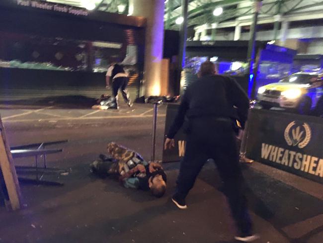 A police officer stands over one of the terrorists after he was shot. Authorities say all three attackers were wearing fake explosives vests. Picture: AFP